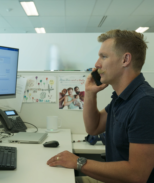 employee on a mobile device sitting in front of a computer