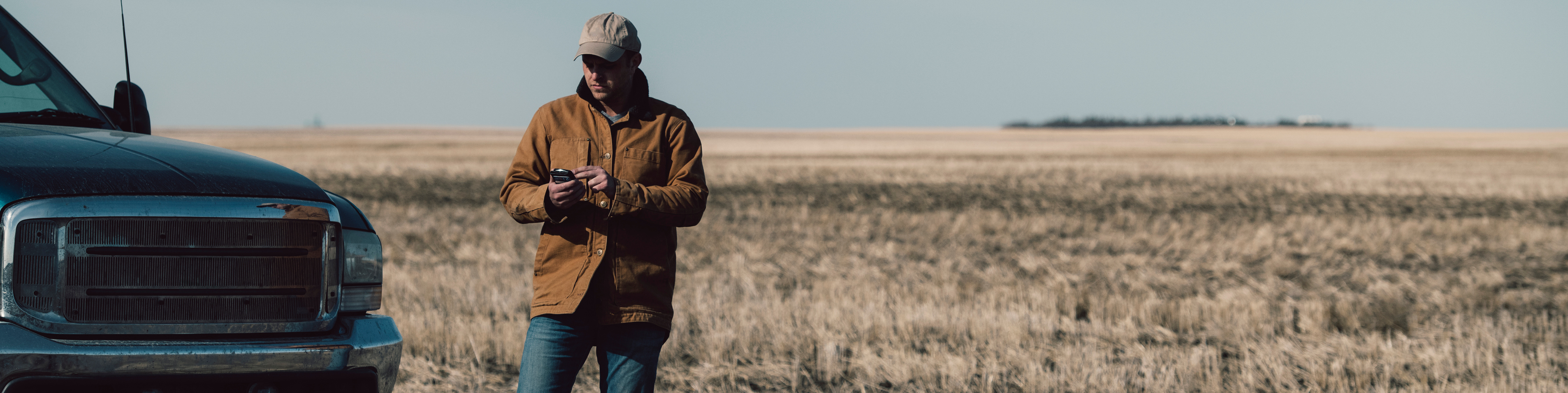 a man standing in front of a field looking at his mobile device