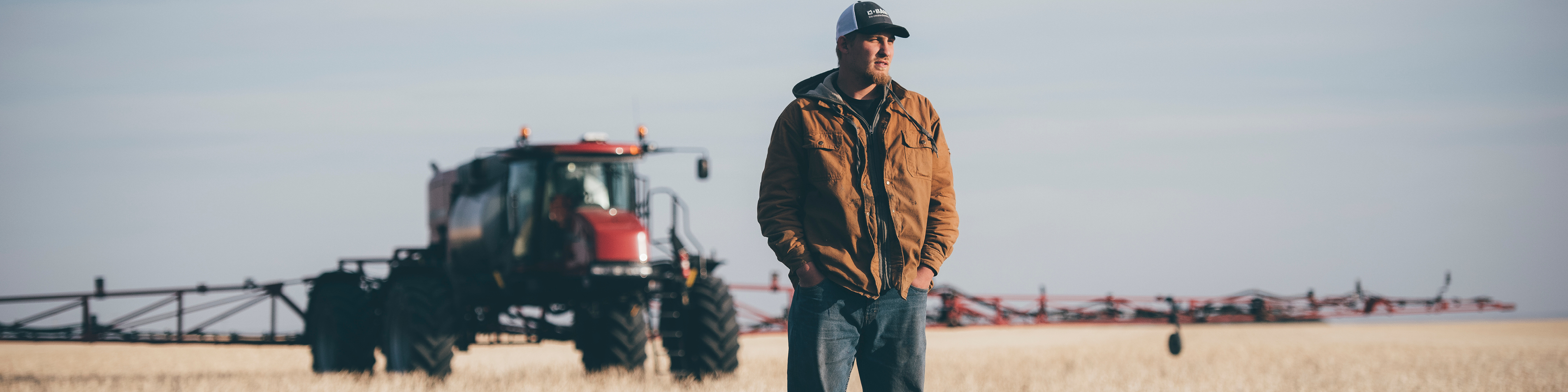 man standing in front of a tractor in a field