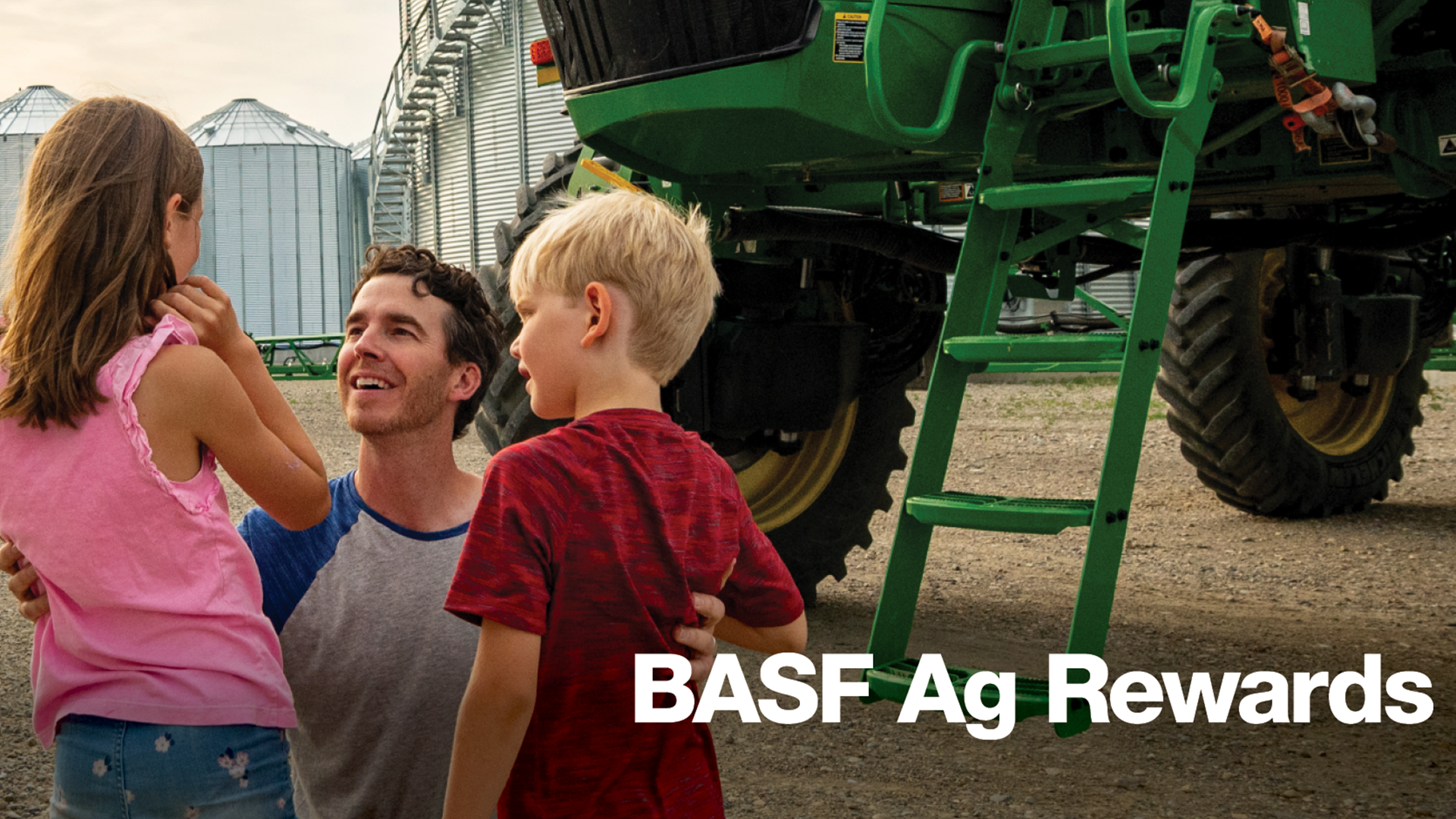Father smiling up at children beside a tractor