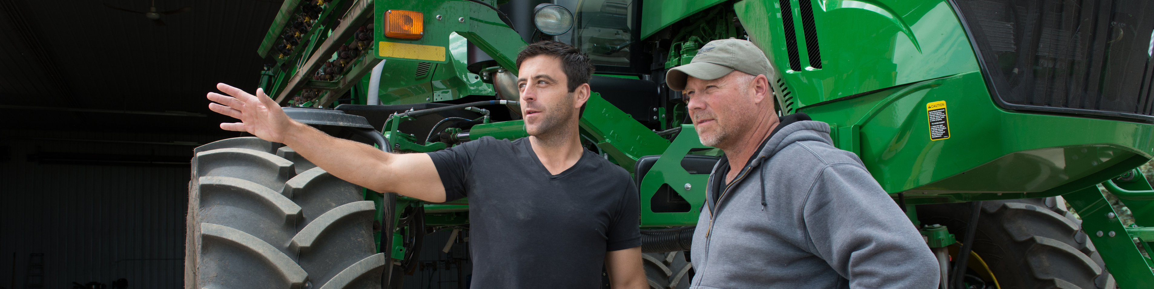 Two people standing in front of a tractor