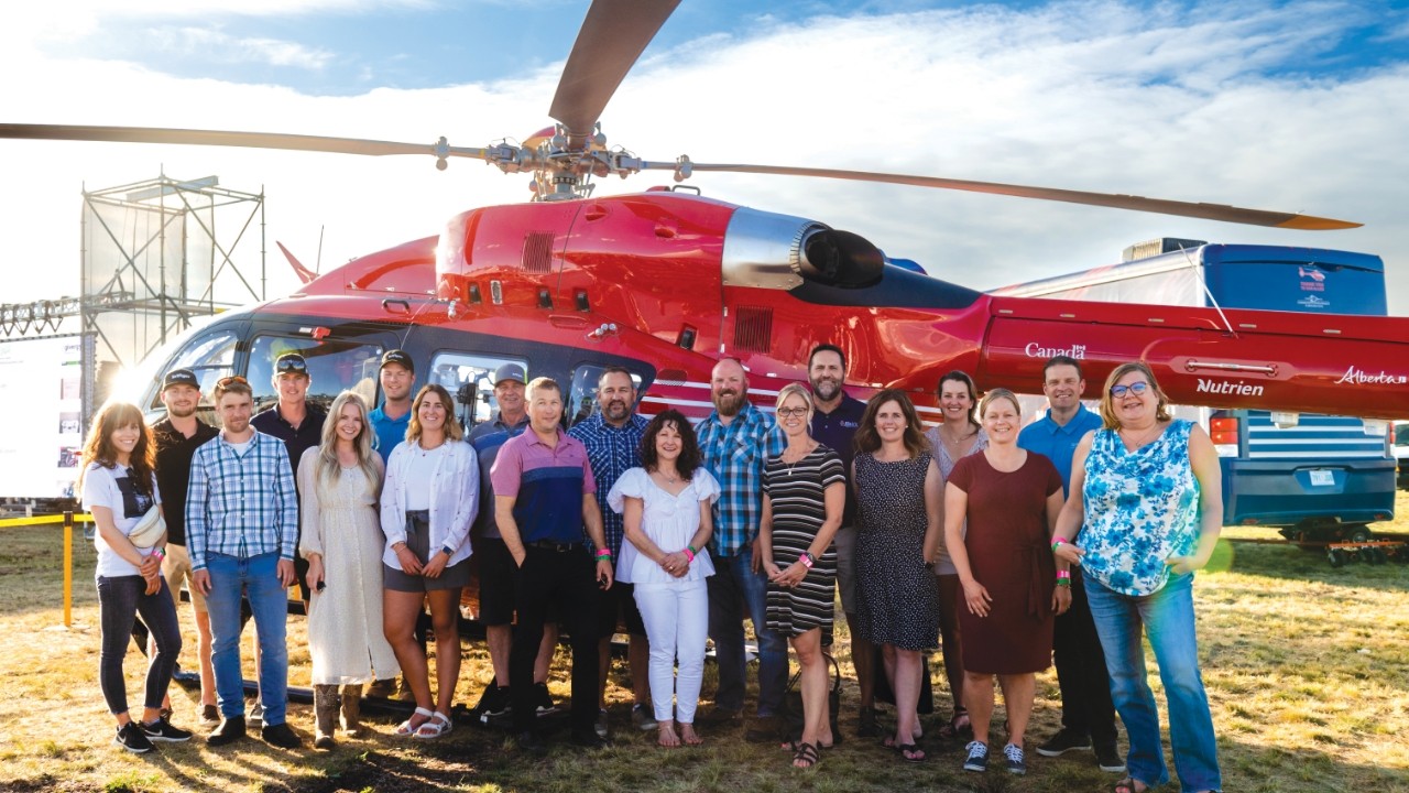 Group of people smiling in front of a helicopter