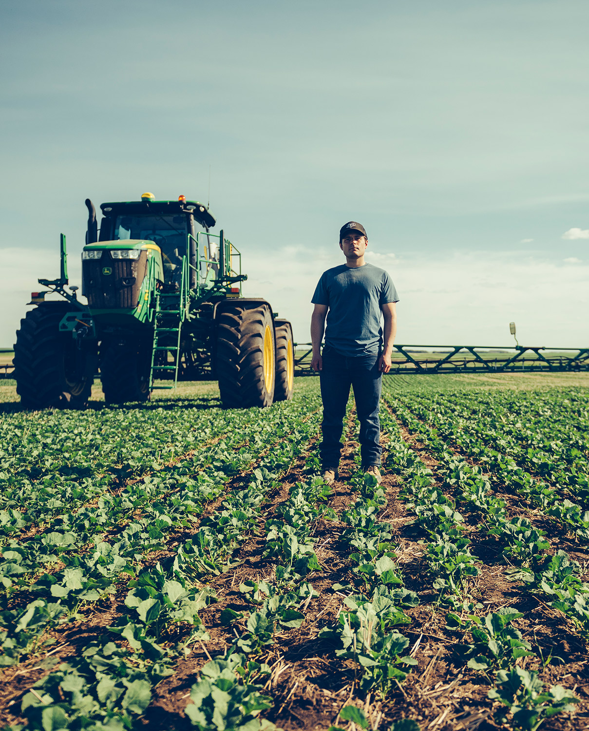 Farmer standing in field with tractor in the background