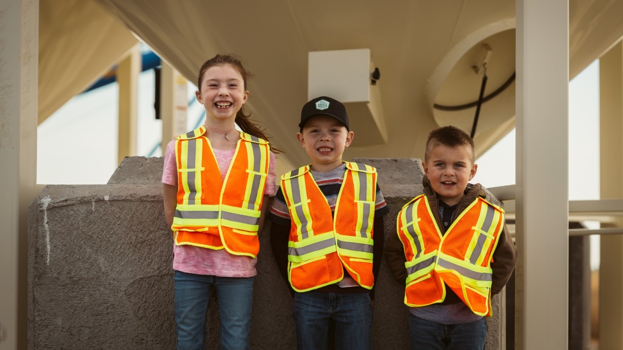 Children smiling wearing orange safety vests