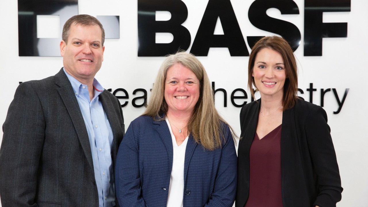Professionals smiling in front of a BASF backdrop