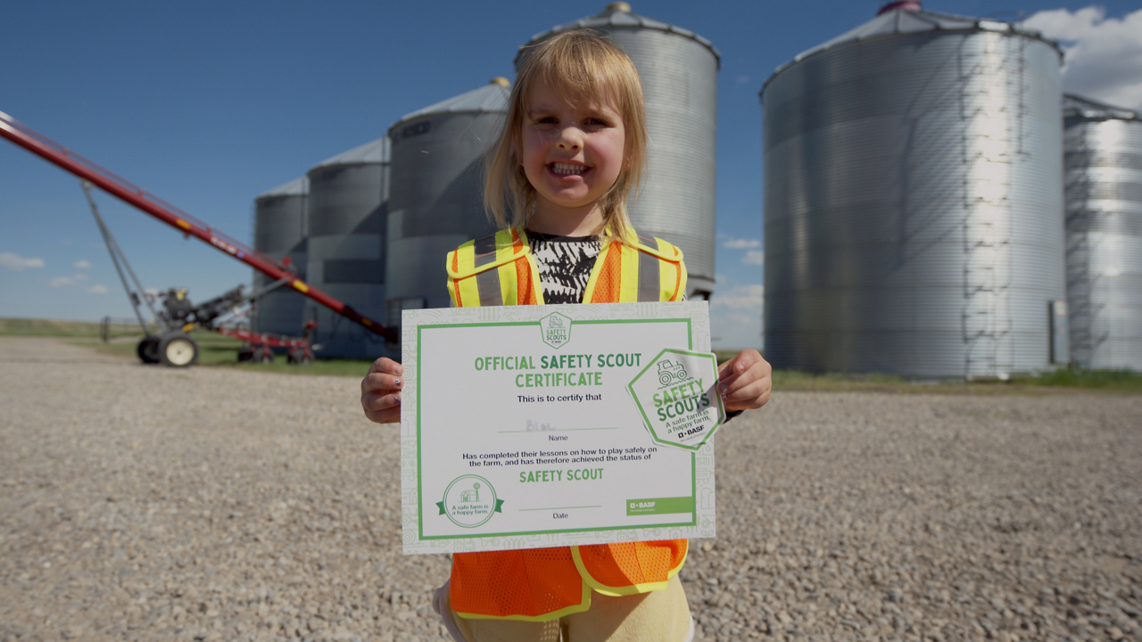 Child smiling and holding a safety scout certificate