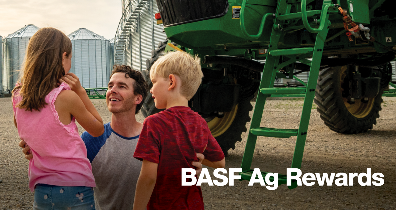 Father smiling up at children beside tractor